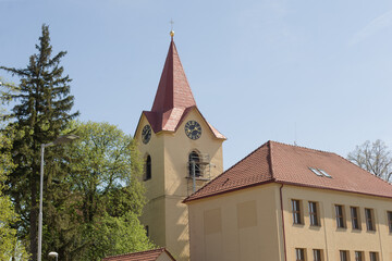 Fototapeta premium A quaint little church, complete with a tall, elegant spire and an adjacent building, set in a peaceful and serene environment