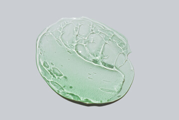 Cosmetic green aloe vera or centella asiatica shaped gel texture swatch isolated on grey background