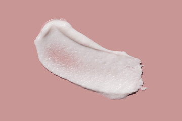 Cosmetic product texture swatch of white exfoliator scrub for lips (or lip mask or lip balm), body or face with micro capsules, sugar or salt isolated on smoky pink background