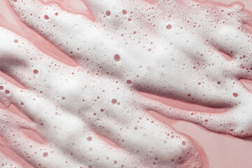 Cosmetic cleansing washing pink soapy foam gel on pink clay ceramic background. Beauty skin care texture