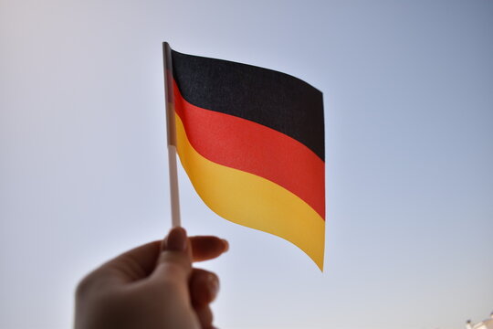 German national flag flying against blue sky &ndash; symbol of patriotism, unity, and the cultural and historical identity of Germany. Ideal for national holidays or international themes.