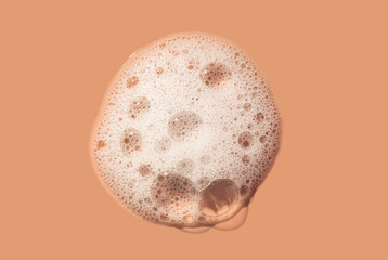 Cosmetic product cleansing washing white soapy foam gel on peach orange isolated background