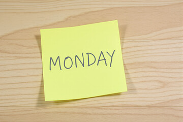 handwritten yellow sticky note with the word on a wooden surface