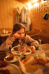 Selective focus. Teenage girl eating in the semi-darkness in a cafe. 