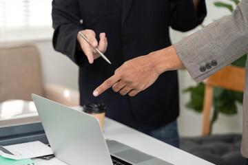 Pointing and Discussion. Two professionals pointing at a laptop screen during a meeting.