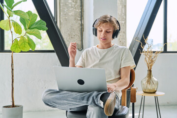 Teenage boy with headphones using laptop for video conference, online meeting