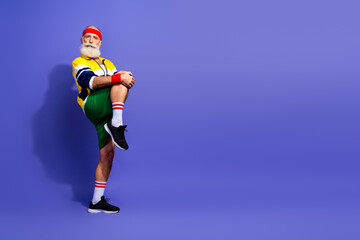 Obraz premium Elderly man in retro athletic wear striking a pose on a colored background embodying an active and stylish lifestyle