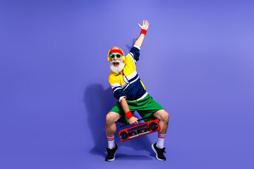 Funny man in vibrant retro-style sportswear enthusiastically posing with a boombox against a...