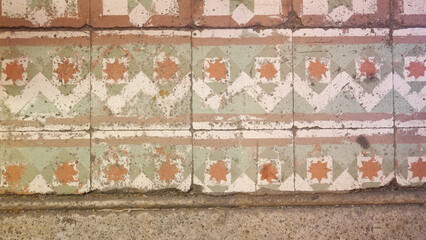 Vintage ceramic floor tiles with faded geometric and star patterns in pastel colors.
