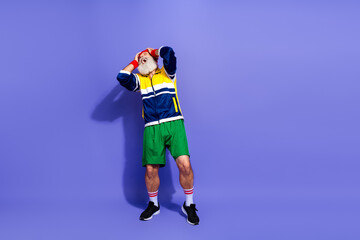 Funny man enjoying active lifestyle wearing retro sportswear, striking a fun pose against a vibrant purple studio background