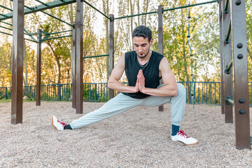 Athletic man in Cossack squat stretch outdoors, improving lower body mobility, hip flexibility, and...