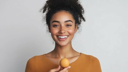 Biracial young woman smiles while holding round bath bomb promoting self-care, body care and well-being.
