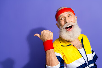 Senior man wearing retro activewear smiling joyfully posing against purple background expressing fitness and nostalgia