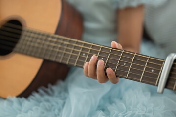 Fototapeta premium Sweet Melody in the Making: Close-Up of a Child's Hand on Guitar Strings, Capturing the Joy of Musical Inspiration and Creative Expression
