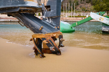 Close-up of a dredging cutter head resting on wet sand at the shoreline, part of a machine used for...