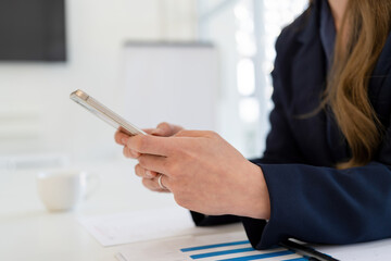 Businesswoman sitting at desk on couch in workplace or at home working on laptop and analyzing data on charts and graphs and writing on papers to make business plan and strategies for company.