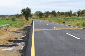 Newly constructed asphalt road with clipping path, asphalt highway road with sky clouds natural landscape, asphalt road passing through agricultural fields under blue sky in Chakwal, Punjab, Pakistan