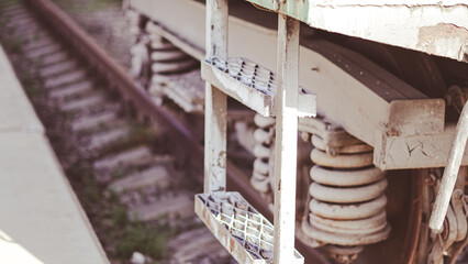 Close up of iron steps of freight train on railway tracks in industrial setting