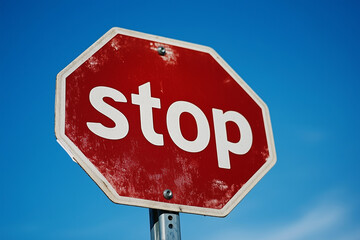 Obraz premium stop sign is on a pole in front of a blue sky. The sign is red and white