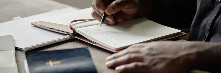Website banner with unrecognizable male hand holding pen while writing in notebook