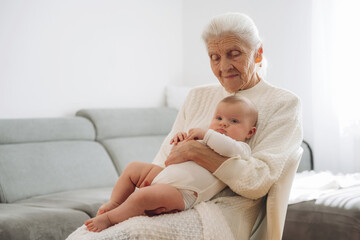 Holding toddler in hands. Grandmother with cute toddler baby at home