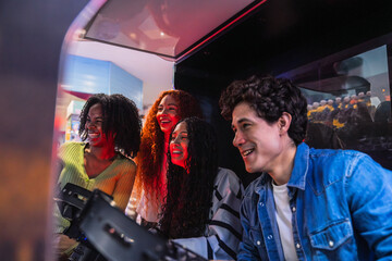 Group of young friends having fun playing arcade video game in a bowling alley, enjoying their leisure time together