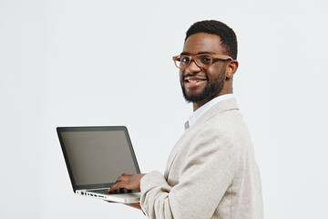 Smiling man holding open laptop in hand, wearing glasses and beige blazer, cheerful expression, professional appearance, isolated on white background, studio portrait, people lifestyle concept