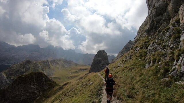 Canazei, Italy &ndash; September 7 2022: Two hikers carefully crosses a rocky ridge on the Colac via ferrata, surrounded by the raw grandeur of Trentino&rsquo;s alpine terrain.