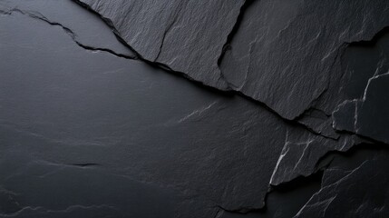 Close-up view of dark grey natural slate stone surface with rough texture and prominent cracks, creating an abstract background.