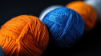 Four vibrant balls of yarn in orange, blue, and white, arranged diagonally on a dark background, showcasing texture and color.