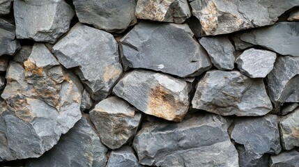 Stone wall displays various sized grey rocks, stacked tightly, creating sturdy rough textured backdrop.
