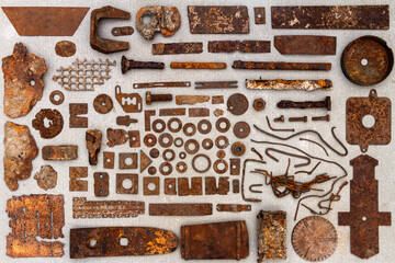 A group of various old rusty bits and pieces arranged on a concrete surface. Old rusty nuts, bolts, nails and other parts flay lay on gray background.