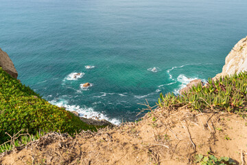 Panoramic view of green hills, rocks and ocean in Cabo da Roca, Portugal