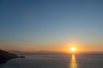 Panoramic view during sunrise over the Tyrrhenian Sea with the Amalfi coastline, Italy on horizon coloring orange in early morning light
