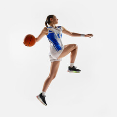 Slam dunk. Side view photo of young fit girl, basketball athlete leaping in mid air to get score...