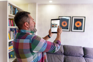 Interior designer using augmented reality app on tablet visualizing artwork placement in client's home