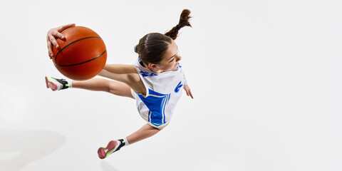 Aerial view of young athletic girl, basketball player in blue uniform raising hand high to get...