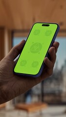 GREEN SCREEN CHROMA KEY A smartphone with a green screen held in a stylish wooden interior apartment with cityscape visible through large windows during the daytime
