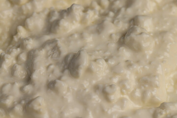 cottage cheese from white milk with sour cream, sprinkled with liquid sour cream, lumps of freshly made fermented milk product