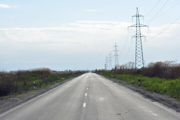 Fototapeta premium High-voltage power lines on the road in the mountains. Road and electric powers