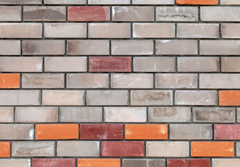 Brick wall with a red brick in the middle. The wall is made of gray and red bricks