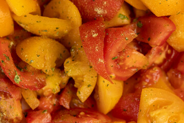 cut tomatoes of red and yellow color during salad preparation, preparation of salad from sliced tomatoes with spices and oil