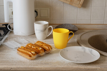 Baked goods arranged on kitchen counter with cups and a plate during morning routine