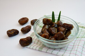 Bowl of Fresh Dates on a Checkered Cloth with Scattered Pieces Nearby