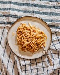 Creamy pasta with cheese and pine nuts on striped cloth.