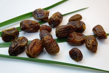 Organic Medjool Dates Arranged on Palm Leaves Against a White Background