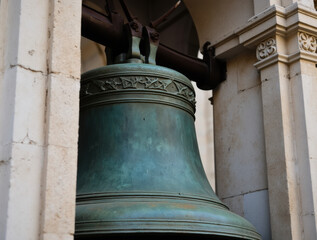 Obraz premium A detailed view of the massive bronze bell with weathered patina and decorative reliefs, framed by the arches of St. Mark’s Campanile, evoking Venetian tradition and history.