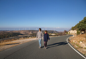Fototapeta premium teenagers - girl and boy walking together on asphalt road on sunny vacation day. Youth, walks, joy, adventures, enjoying sunny day. Spending time together on vacation