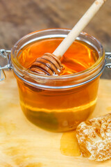 honey in a jar with honeycomb on a wooden table
