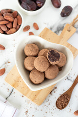 Cocoa date chocolate truffles in heart shaped plate on kitchen table. Top view.